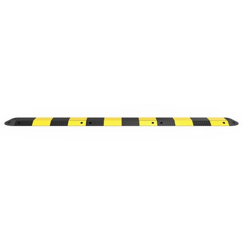 Eye-level shot of a black and yellow striped speed bump. The speed bump is long and narrow, with rounded edges and several small holes along its length.