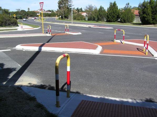 Traffic control with barrier rails for pedestrian safety. Road intersection with traffic calming measures and pedestrian crossing.