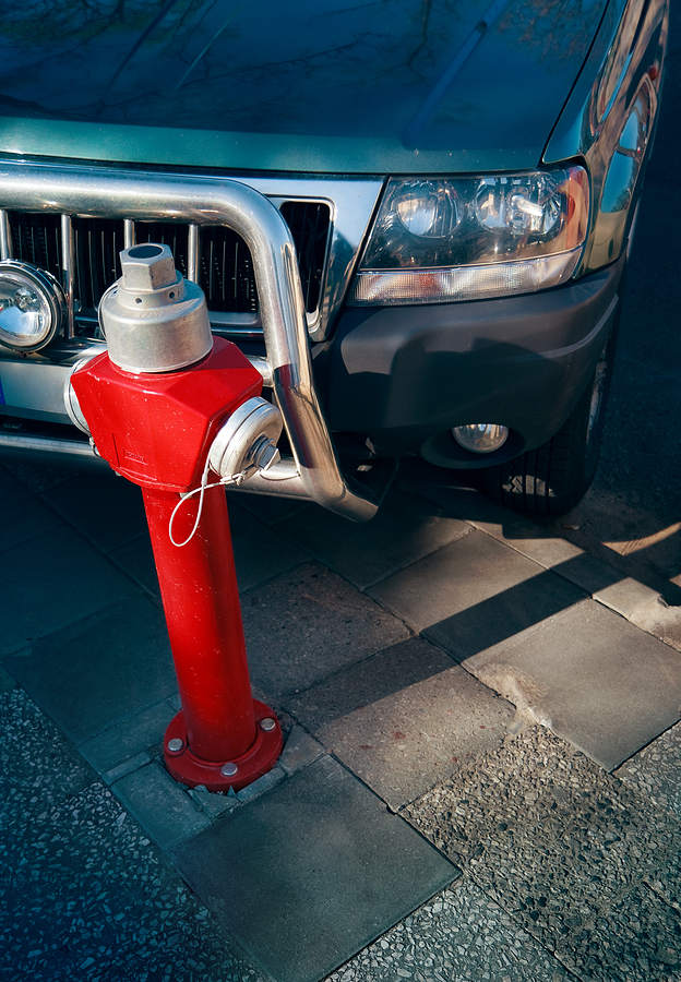 Red fire hydrant near a parked car. Should you park in front of a fire hydrant? Parking too close can obstruct access in emergencies.