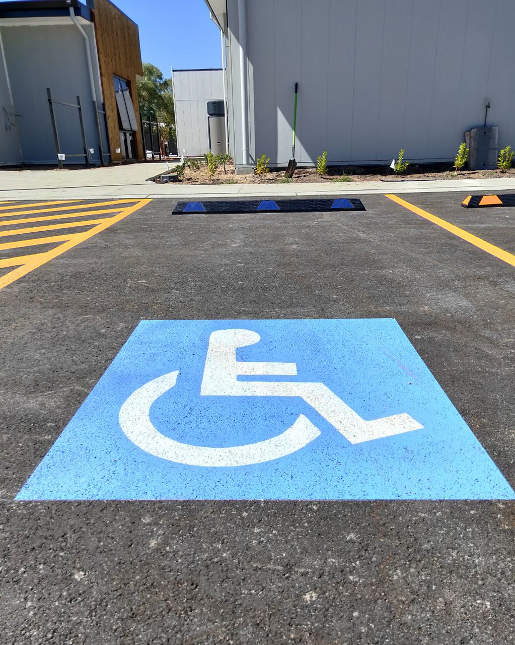 DRWSB e1715752424455 Dugite Rubber Wheel Stop 1650mm x 95mm Blue 2 Handicap parking spot with a blue Dugite Rubber Wheel Stop 1650mm x 95mm. The parking spot is marked with a blue handicap symbol.