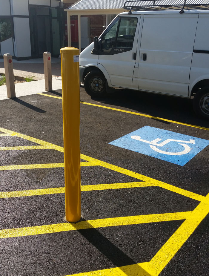 Permanent Bollards for Disabled Parking Bays Effective Placement of Permanent Bollards on Larger Disabled Car Parks 1 Permanent bollard placement on disabled car parks. Yellow bollard in a disabled parking space with yellow lines and a white van in the background.