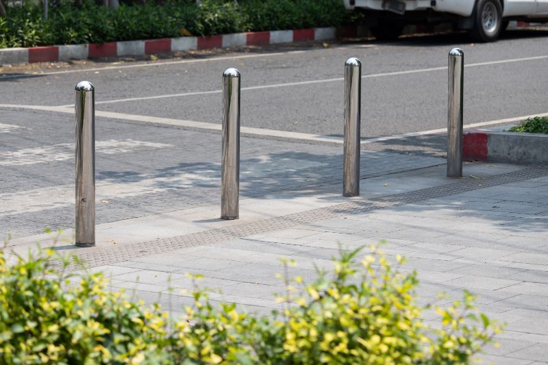 Stainless Steel Bollards 1 School Safety: School Traffic Management Plan 1 School safety traffic management plan: Four bollards on a sidewalk near a street with a vehicle in the background, ensuring pedestrian safety.