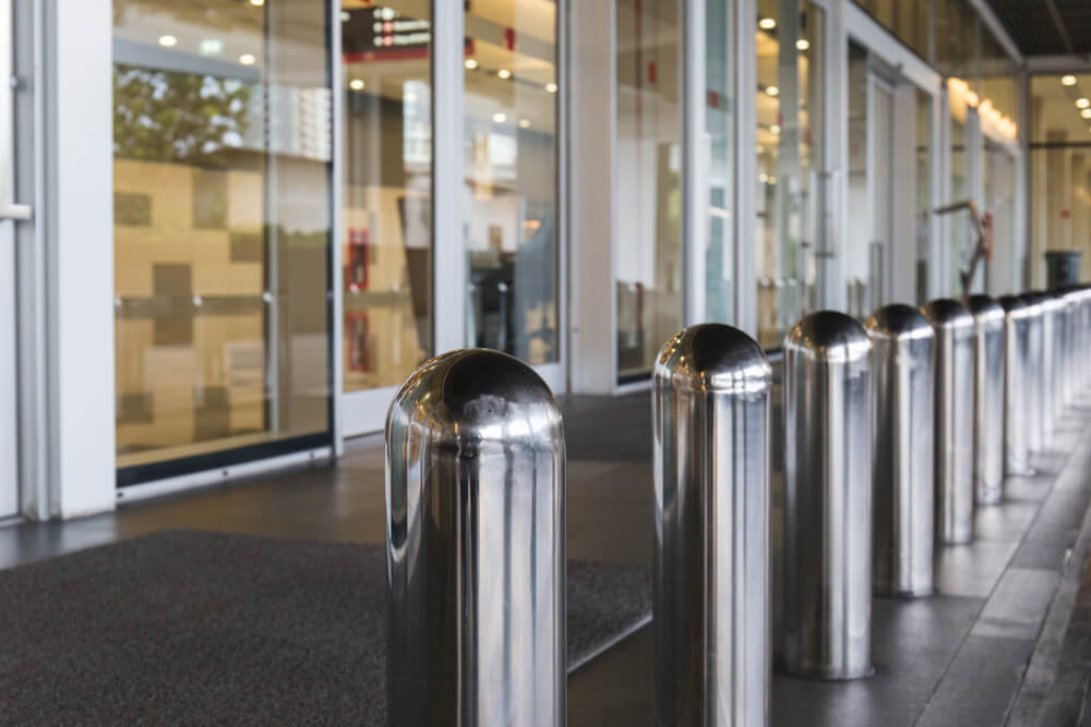 Bollard installation: Row of stainless steel bollards outside a building entrance. Security bollards protect against vehicle impacts.