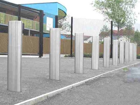 Row of steel bollards installed for security. Silver metal bollards protect a building, enhancing safety and access control at the location.