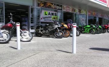 bollards Bollards Humble Beginning 1 White bollards protect motorcycles parked outside a store. Bollards are a type of safety barrier that will suit your needs best for traffic management.