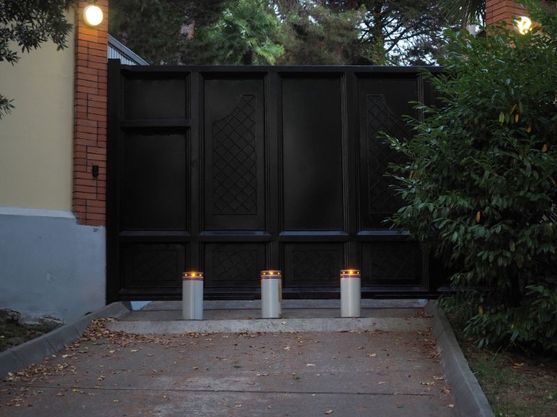 Black sturdy fencing to protect home with bollards in front of a gate. The fencing will stop a car.