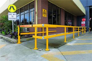 Yellow safety barrier near a warehouse entrance, promoting pedestrian safety. Signage indicates Give Way To Pedestrians and a forklift hazard warning.