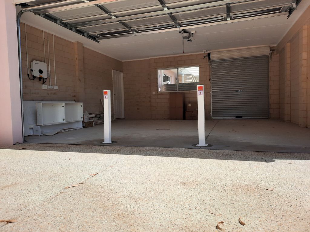 image 1708052991818502 Dugite Bronze 90mm x 900mm Retractable Bollard 2 Garage view featuring two white 90mm Dugite Bronze retractable bollards, providing security. The bollards stand guard in an open space.