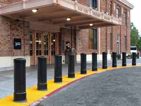 installing security bollards Installing Security Bollards 1 Security bollards installed in front of a brick building. Black bollards line a yellow walkway, enhancing safety and security at the entrance.