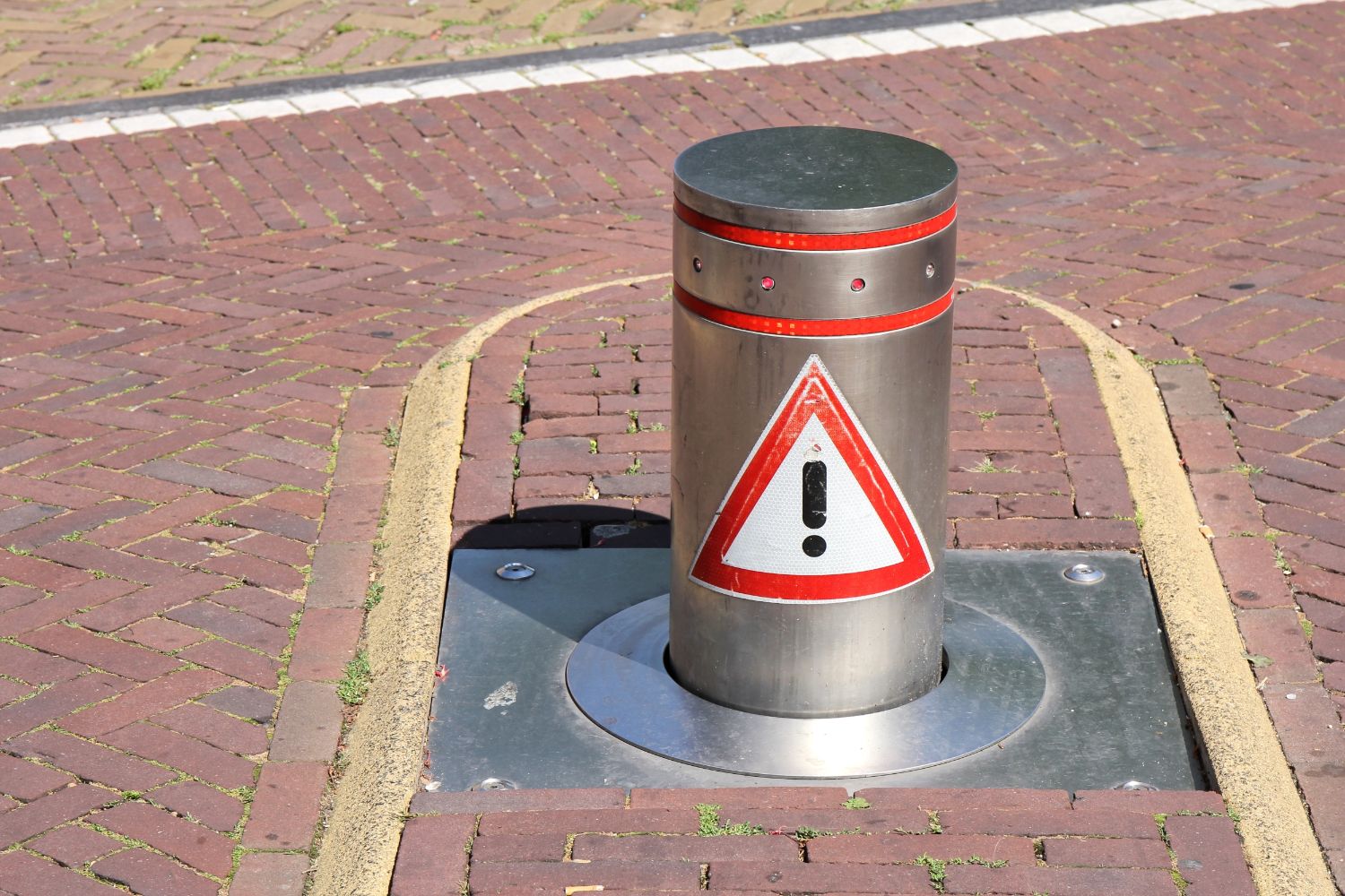 Domestic bollard on brick road, featuring a warning sign. Bollards can save you money by preventing damage.