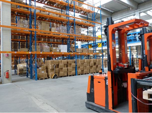 Warehouse interior with safety barriers, shelving, boxes, & forklifts. Safety must-haves for warehouse operations, including barriers.