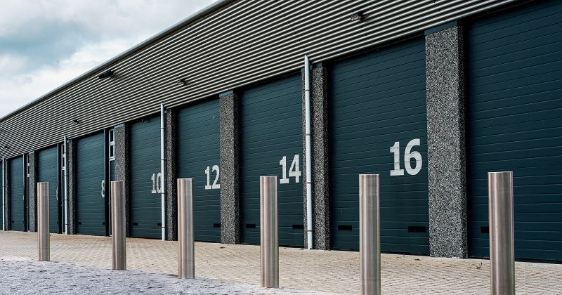 Steel bollards in front of numbered storage units. Metal bollards protect the doors. Security and safety with steel bollards.