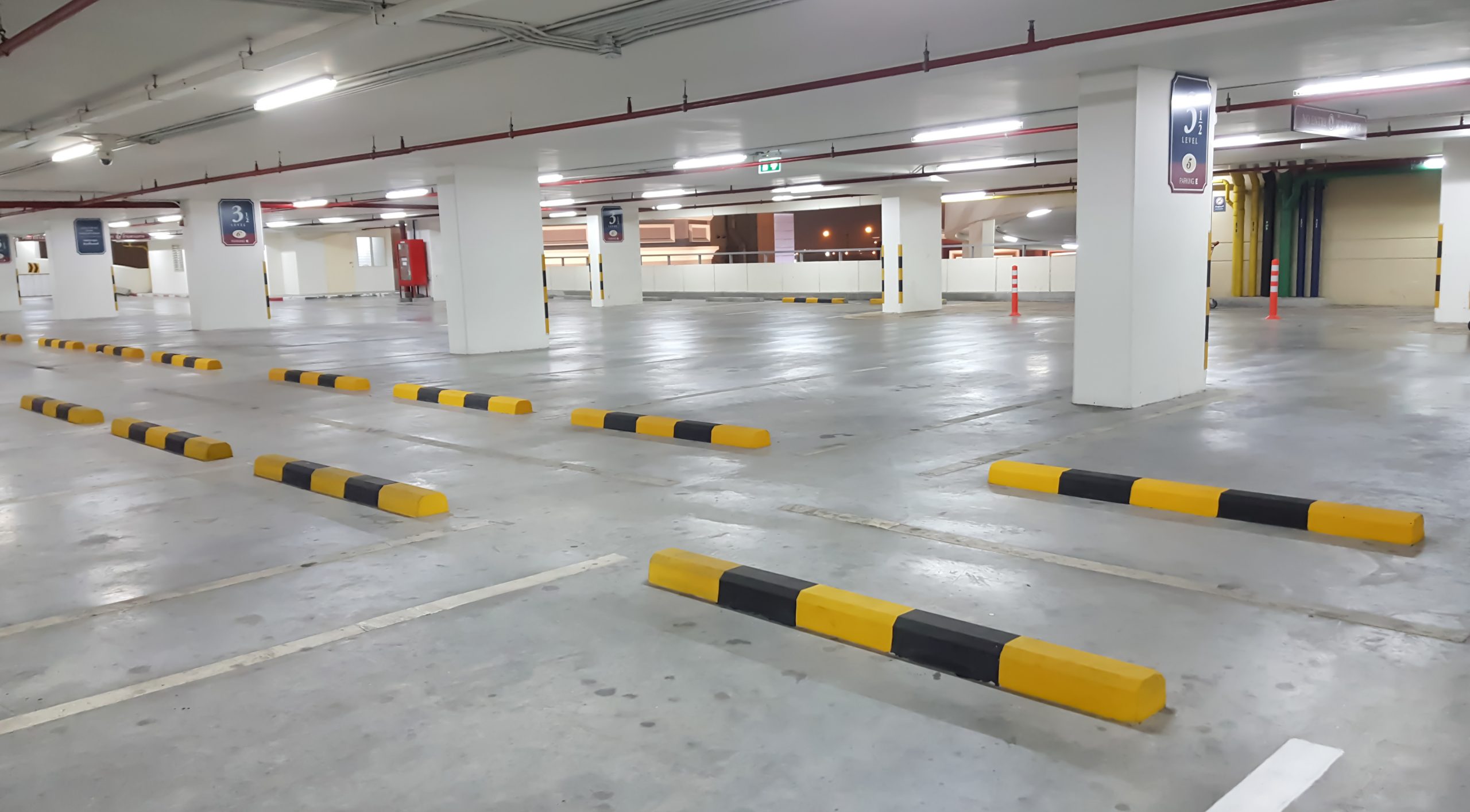 wheel stops in car parking scaled 1 Wheel Stop Installation Guide For Your Parking Lot 1 Parking lot with installed wheel stops. Yellow and black wheel stops in parking spaces. Wheel stop installation guide.